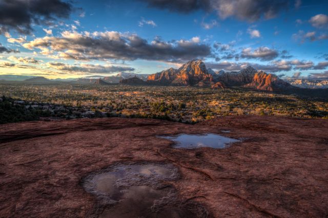 Showing the majestic view of Sedona's rugged red rock formations under a dramatic sunset sky with clouds. This can be used for travel brochures, outdoor adventure websites, nature desktop wallpapers, and promotional material highlighting Arizona's natural beauty.