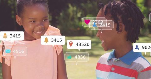 Smiling children with social media notification overlays on sunlit park lawn