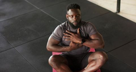 Meditating african american man practicing breathing techniques in gym