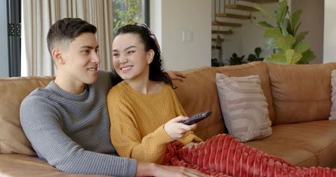 Couple Relaxing with TV Remote on Comfortable Sofa