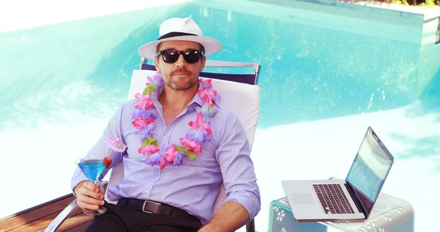 This scene is perfect for advertisements and blogs focused on remote work, summer getaways, or the concept of a work-life balance. The businessman wearing a lei while holding a martini exudes a vibe of relaxation and enjoyment in a tropical setting. The presence of the laptop suggests that work can be conveniently managed from beautiful locations, ideal for use in travel or remote work promotions.