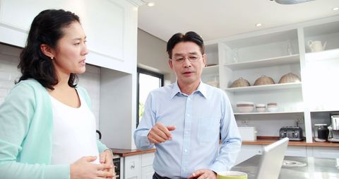 Middle-aged couple engaging in serious discussion in modern kitchen