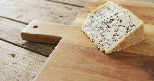 Image of wedge of blue cheese on chopping board, on rustic wooden table. quality, tasty light food snack.