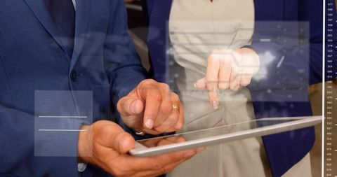 Business professionals pointing and tapping tablet with futuristic data overlays
