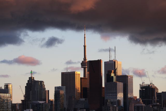 Capturing the Toronto skyline during sunset, this image showcases a landscape of towering skyscrapers under dramatic cloud formations. Perfect for travel blogs, city lifestyle articles, and architectural portfolios, it conveys an urban atmosphere and vibrant city life.
