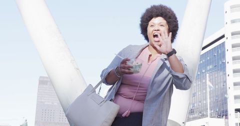 Cheerful plus size biracial woman waving in city