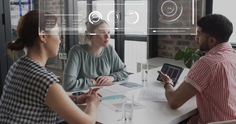 Creative team discussing marketing presentation around white table with tablet and charts