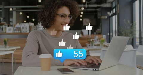 Smiling young man typing on laptop at cozy cafe with floating like icons and 55 notification