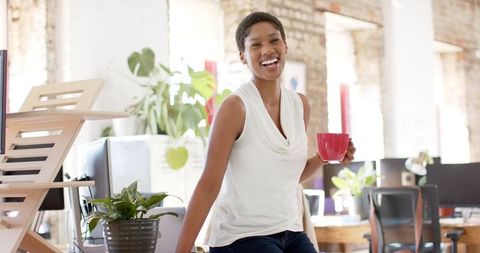 Cheerful Businesswoman Relaxing With Coffee in Modern Office Space