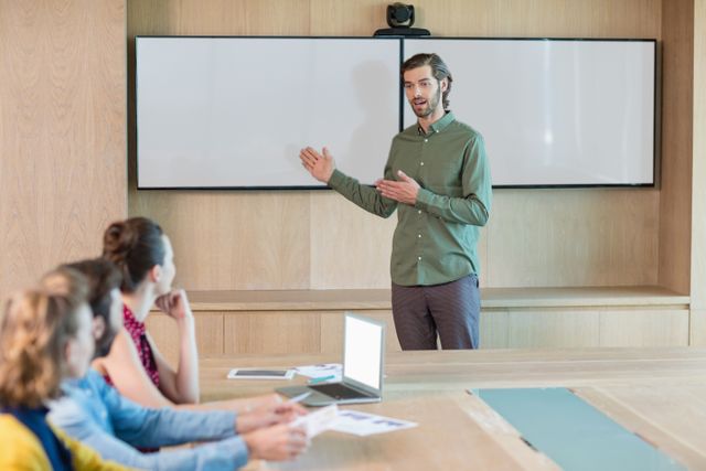 Business executive giving a presentation to colleagues in a modern conference room. Ideal for use in articles about corporate meetings, teamwork, business strategies, professional development, and leadership training.