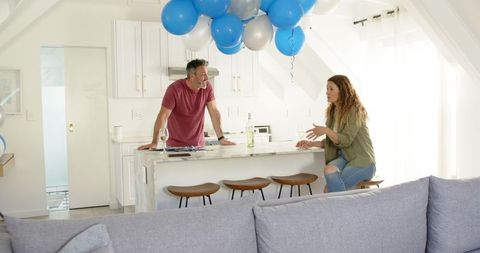 Mature Couple Conversing in Modern Kitchen with Balloons