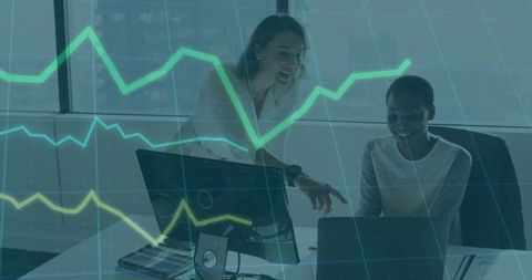 Two Women Collaborating on Data Analytics with Laptop Displaying Green Charts in Office