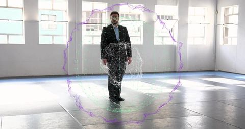 Businessman standing in empty studio interacting with futuristic wireframe sphere