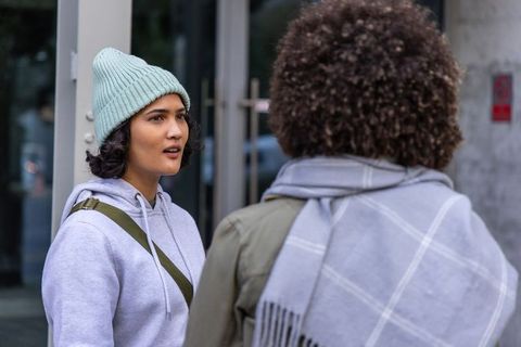 Young women talking outside wearing beanie, hoodie and scarf