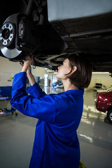 Female mechanic fixing a car wheel disc brake in repair garage