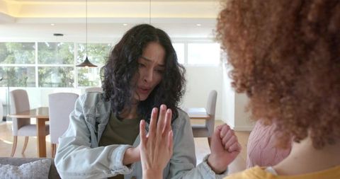 Friends arguing on couch raising hand during heated confrontation in modern living room