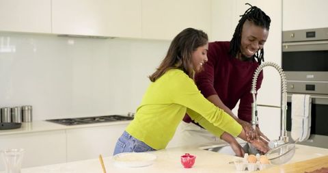 Rinsing hands together while baking in bright modern kitchen with spring faucet