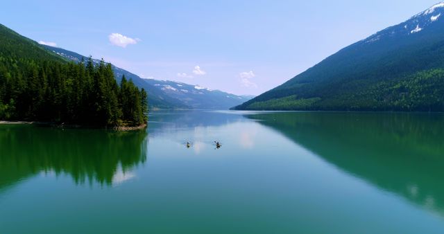 Two people are kayaking on a tranquil mountain lake, with copy space. The serene waters and surrounding forest create a peaceful setting for outdoor activities.