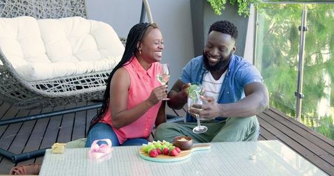 Joyful Couple Enjoying Relaxing Drinks on Stylish Patio