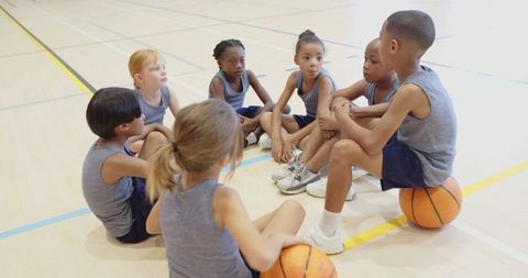 Diverse Young Basketball Team Strategizing in Gym
