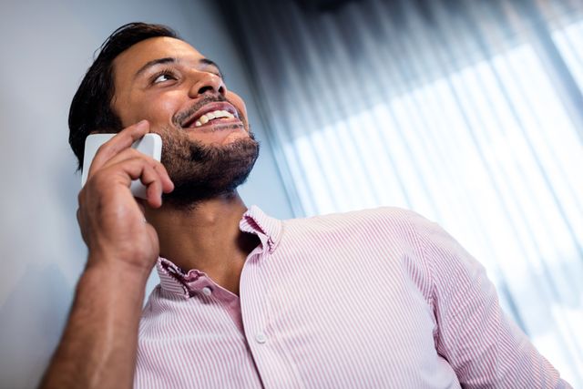 Focus on smiling businessman calling with smartphone in studio 