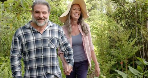 Joyful Senior Couple Walking Hand in Hand Through Green Garden Path