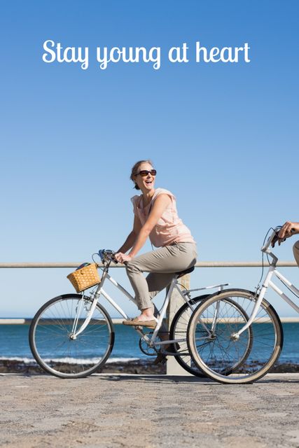 Promoting a healthy lifestyle, a joyful woman cycling by the sea embodies vitality and happiness. This image can also inspire travel and leisure content, emphasizing active vacations.