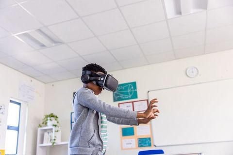 African american student wearing vr headset reaching forward for immersive learning in classroom