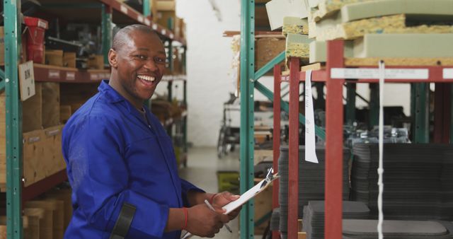 Smiling Factory Worker in Blue Overalls Holding Clipboard in Warehouse - Download Free Stock Images Pikwizard.com