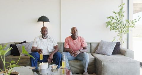 Father and Son Bonding Over Drinks and Snacks in Cozy Living Room