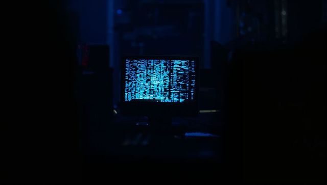 Neon Blue Digital Code Display on Monitor in Dim Server Room
