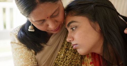 Mother comforting daughter at home in loving embrace