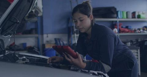 Young Female Mechanic Using Tablet for Car Engine Diagnostics