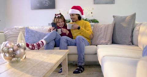 Couple enjoying cozy Christmas evening on sofa wearing Santa hat and reindeer headband