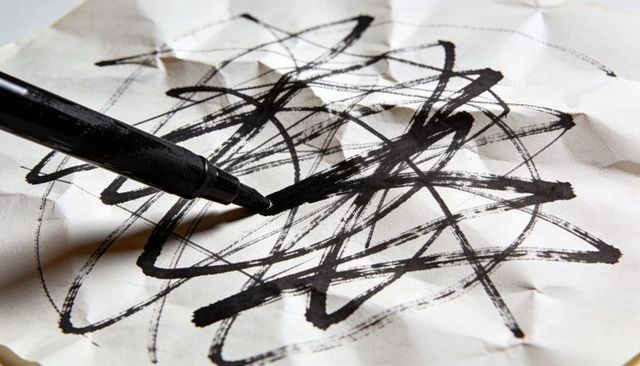 Crumpled Paper with Bold Black Marker Scribbles Closeup Conveying Creative Frustration, Ink Strokes