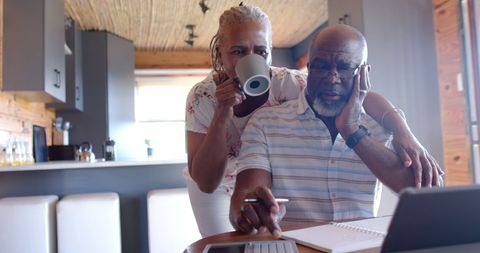 Happy Senior Couple Managing Finances Together on Laptop