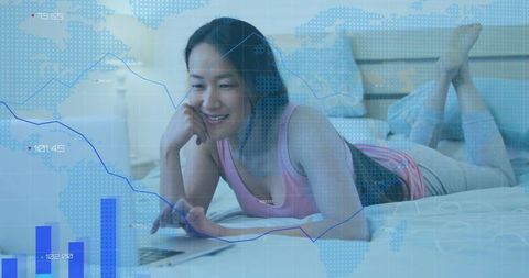 Korean woman working remotely on laptop in cozy bedroom with financial data overlay