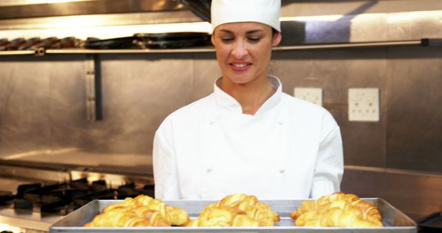 Professional Female Chef Holding Tray of Freshly Baked Croissants in Kitchen - Download Free Stock Photos Pikwizard.com