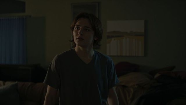 Teen male standing in dim bedroom at night, looking left, moody nocturnal portrait