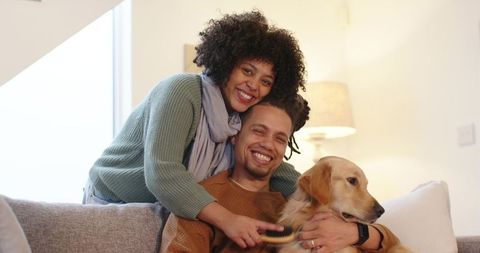 Couple cuddling on couch brushing golden retriever, cozy home pet care and affection
