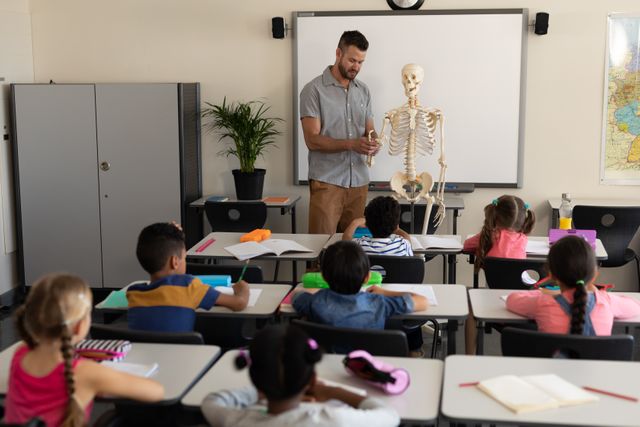 Far sight of male teacher explaining human skeleton model in classroom  - Download Free Stock Photos Pikwizard.com