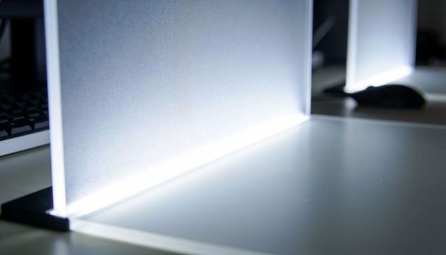 Glowing frosted divider casting led light across minimalist office desk and workstation