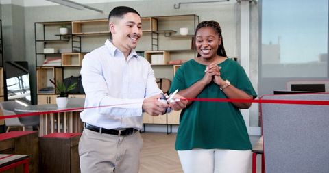 Colleagues cutting ribbon celebrating office opening ceremony