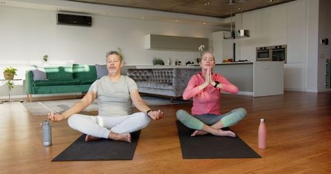 Senior Couple Meditating on Yoga Mats in Modern Home Interior