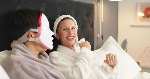 Couple enjoying at-home led skincare session in cozy bedroom robes relaxing together