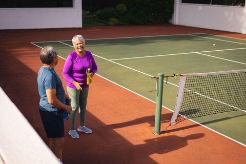 Active senior couple enjoying tennis on bright day