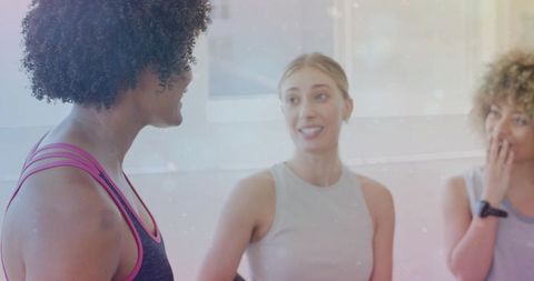 Fit friends chatting after workout in bright studio wearing activewear and fitness tracker