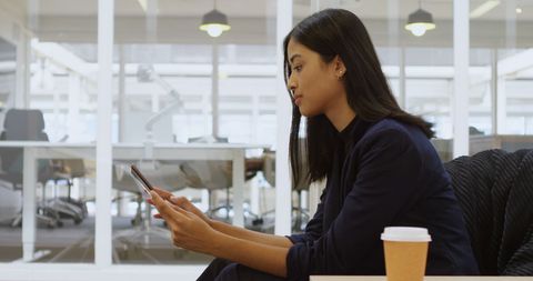 Focused Young Woman in Office Engaged with Smartphone