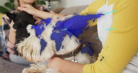 Women petting dogs on couch with blue digital world map overlay, cozy domestic companionship