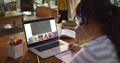 Girl Wearing Headset Studying at Home Taking Notes During Online Class on Laptop